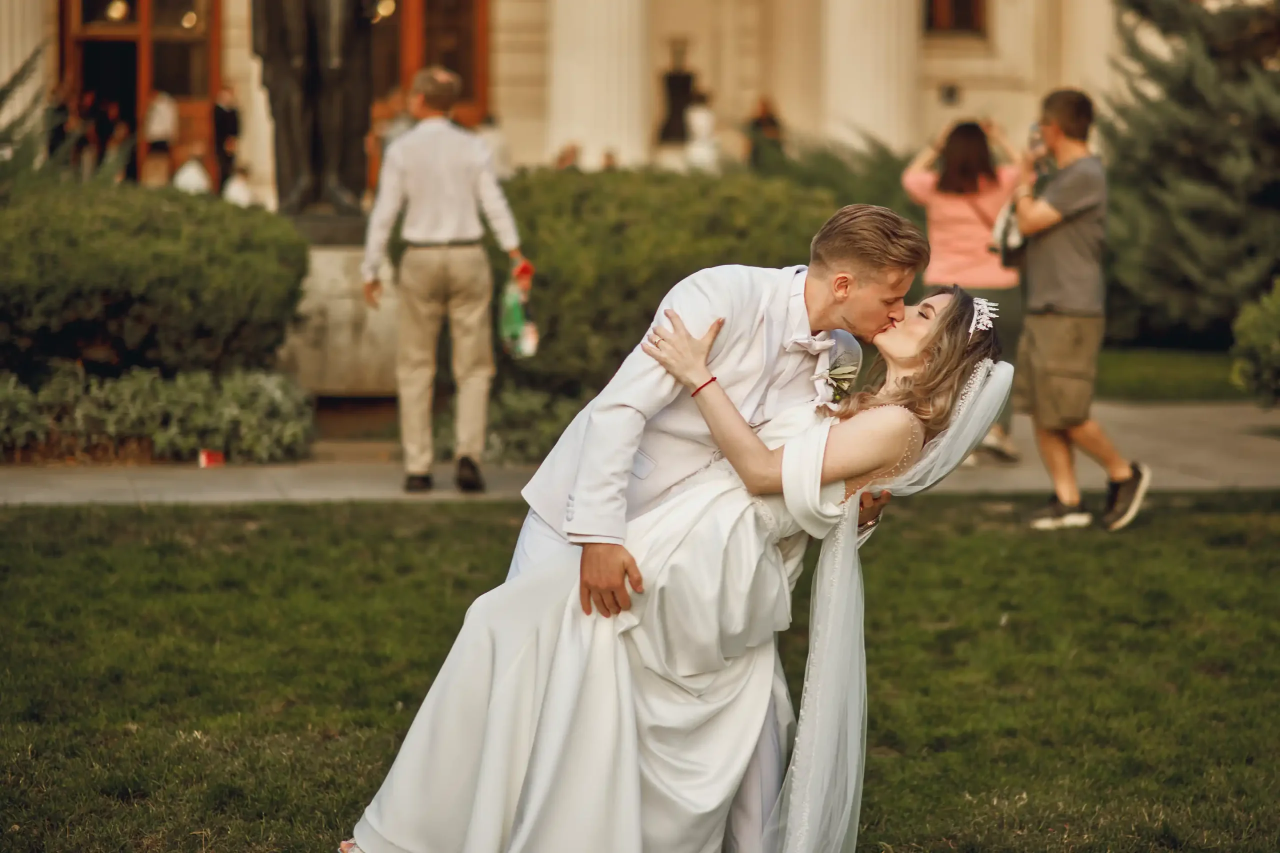 Mirele sarutand mireasa intr-un moment romantic surprins de un fotograf profesionist Bucuresti in fata Ateneului Roman, simbol al elegantei si iubirii eterne